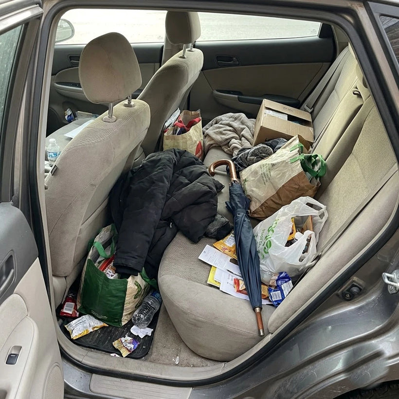 Bags and coats piled on a messy back-seat floor