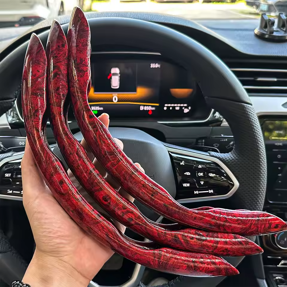 Red decorative items held in front of a car's dashboard display.