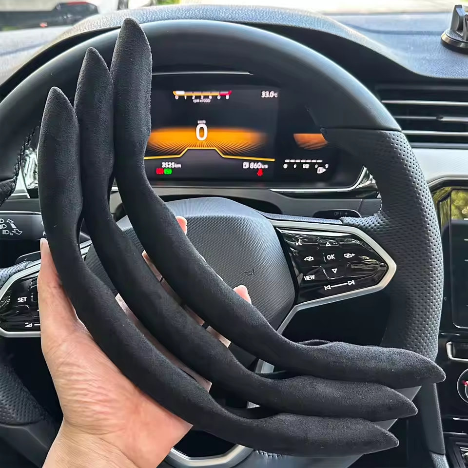 Steering wheel cover held in front of a car dashboard with digital display