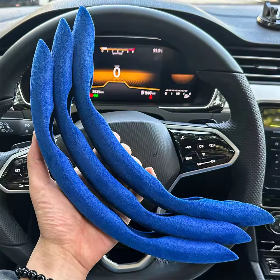 Blue car air freshener strips held in front of a car's steering wheel and dashboard.