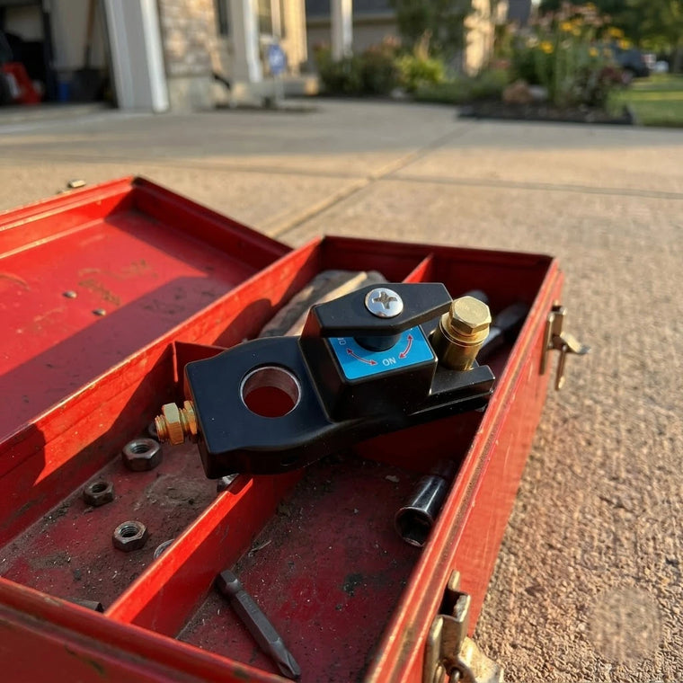 BOLTHUT battery disconnect switch resting beside a car battery in daylight