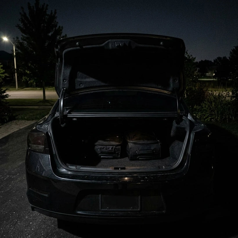 A dark car trunk at night with bags barely visible